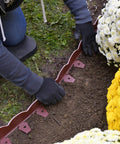 Person installing Scalloped Top No Dig Landscape Edging With Extra Anchoring Spikes In Red 100 Foot Kit Flexible Recycled Plastic Border