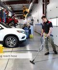 Man using the Pro Wall Mounted Garage And Car Vacuum With 50 Ft Hose And Tools, 7 Gallon Capacity in a workshop.