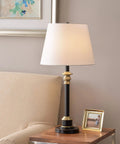 Two Tone Oil Rubbed Bronze And Antique Brass Table Lamp With Crisp White Tapered Shade on a Living Room Desk