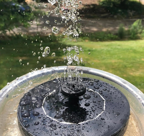 Solar Powered Bird Bath Fountain Pump Kit With 1.3W Panel Outdoor Submersible Water Pump spraying water in a garden setting