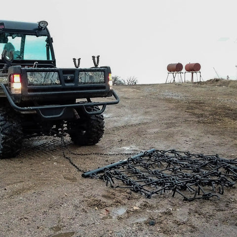 Rugged 6 Foot By 4 Foot Tow Behind Drag Harrow With Powder Coat Black Finish attached to ATV on soil field