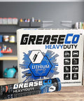 Greaseco Heavy Duty Lithium Complex grease tubes and box on a workbench in a garage setting.