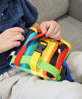 Child interacting with Colorful Buckle Pillow Sensory Toy For Fine Motor Development And Kid Friendly Hands On OT Therapy With Threading Counting Latches And Zipper Skill Practice SENSORY4U Plushie on sofa
