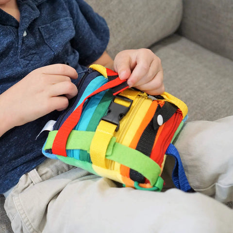 Child interacting with Colorful Buckle Pillow Sensory Toy For Fine Motor Development And Kid Friendly Hands On OT Therapy With Threading Counting Latches And Zipper Skill Practice SENSORY4U Plushie on sofa