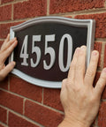 Hands using Heavy Duty Double Sided Mounting Tape Weatherproof 1 Inch By 60 Inch Black Pack Of 3 That Holds Up To 30 Pounds to mount sign