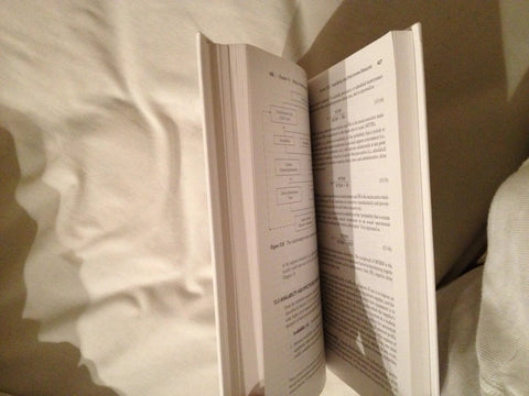 Book: Systems Engineering and Analysis, open pages with diagrams and dense text on a bed.