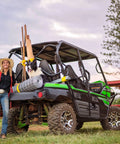 Woman with a dog and farm supplies on an ATV in a rural paddock setting.