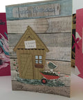 Birthday card with garden shed design and greeting on wooden panel background.