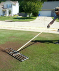 Person using 30-Inch Lawn Leveling Rake with 72-Inch Handle, stainless steel tray, in garden for effortless leveling.