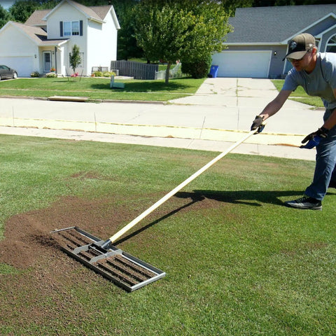Person using 30-Inch Lawn Leveling Rake with 72-Inch Handle, stainless steel tray, in garden for effortless leveling.
