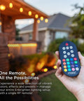 Hand holding remote control for Color Changing LED Garden Lights Kit with pathway lights in the background