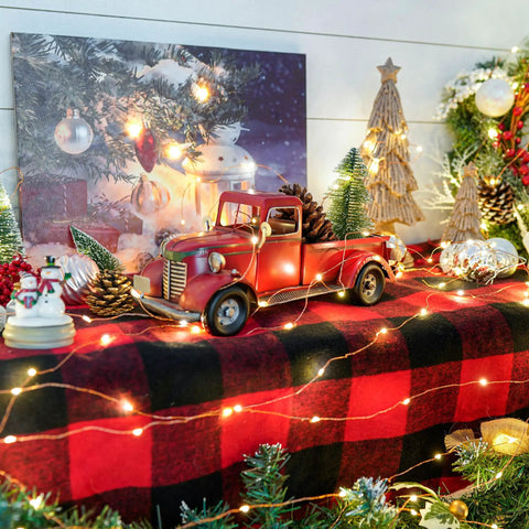 Iron Classic Red 12 Inch Pickup Truck Figurine For Home Decor amidst Christmas lights and ornaments on a festive table.