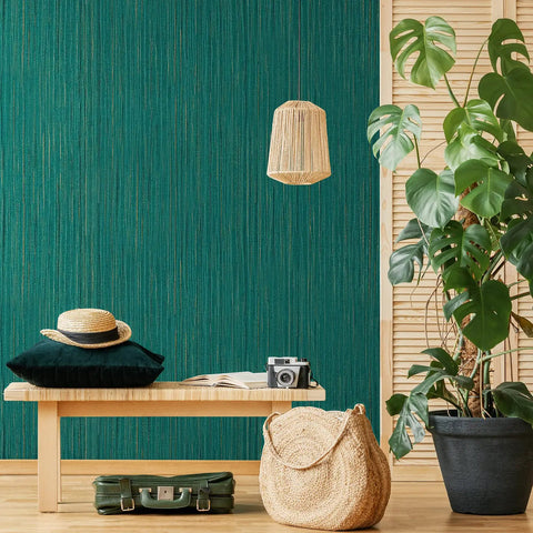 Interior with teal green grasscloth peel and stick wallpaper on wall, featuring a bench, plants, and a woven pendant light.