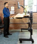 Smooth Bamboo Electric Standing Desk Riser 60 X 30 Inches with motorized lift, adjustable height, and easy rolling casters used in a home office.