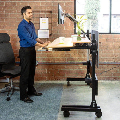 Smooth Bamboo Electric Standing Desk Riser 60 X 30 Inches with motorized lift, adjustable height, and easy rolling casters used in a home office.