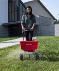 Person using Beefy Workhorse Walk Behind Broadcast Spreader For Grass Fertilizer And Seeds With 65 Pound Hopper on lawn