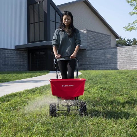 Person using Beefy Workhorse Walk Behind Broadcast Spreader For Grass Fertilizer And Seeds With 65 Pound Hopper on lawn