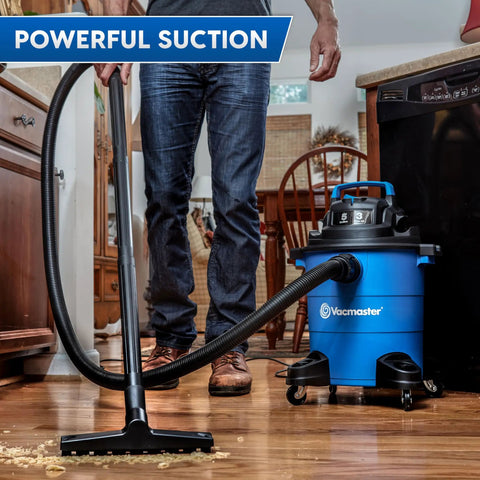 Person using 5 Gallon Wet And Dry Shop Vacuum With 3 Peak HP 65 CFM 16 Foot Reach Includes 8 Accessories With Cartridge Dry Filter And Foam Wet Filter VOC507PF Great For Home Or Shop Cleanup on kitchen floor.