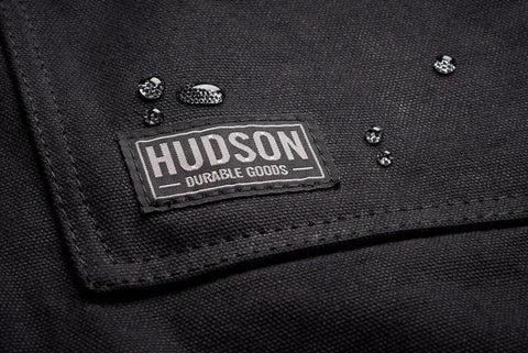 Close-up of black Heavy Duty Waxed Canvas Apron for Men and Women, Adjustable Crossback with Tool Pockets, water beads on fabric