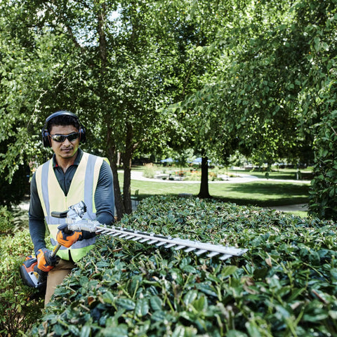Man using power trimmer wearing lightweight headband ear protectors with padded headband and clamshell design 25dB NRR.