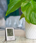 Wireless Indoor And Outdoor Temperature Monitor With Humidity Hi Low Records 12 And 24 Hour Time 330 Ft range displayed near plant
