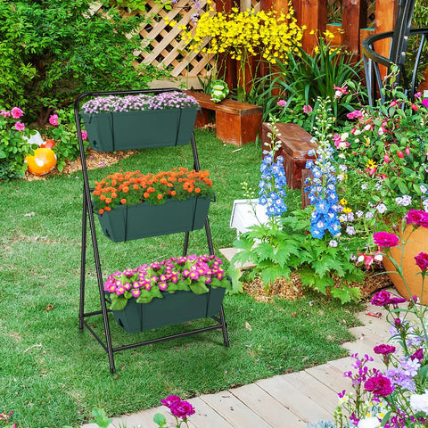 3 Tier Vertical Raised Garden Bed Standing Planter Box For Vegetables Herbs And Flowers Indoor Outdoor Space Saving Garden Organizer In Green Easy Assembly Ready To Go For Any Balcony Or Patio And Built To Last in a garden setting with colorful flowers.