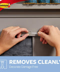 Hands removing a clear mini light clip for damage-free decorating from a gray surface, no nails or glue needed.