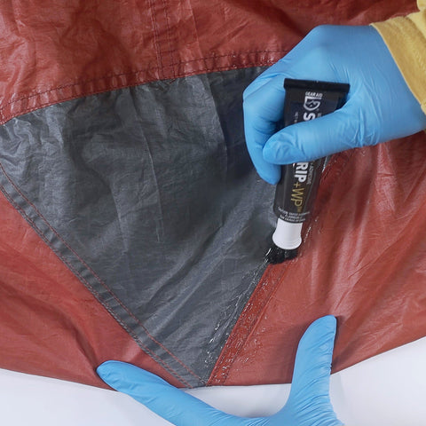 Applying Seam Grip WP Waterproof Sealant And Adhesive For Jackets Tents Tarps Rain Gear And Outdoor Fabric on a tent seam