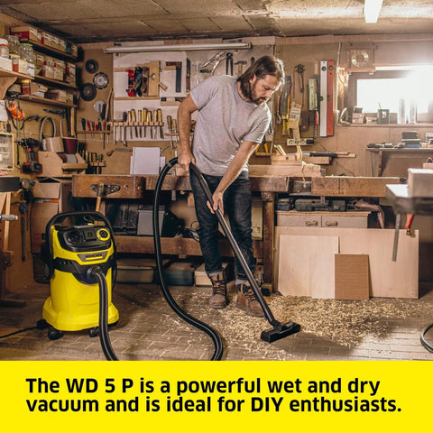 Person using WD 5 P Shop Vacuum 6.6 Gal Wet Dry Vacuum Cleaner with 33 Ft Reach in a workshop setting.