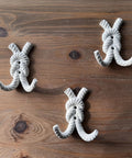 Top Shelf Nautical Rope Knot Wall Hooks Set Of Three Tough Cast Iron Antique White Finish mounted on wood.