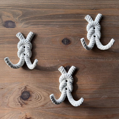 Top Shelf Nautical Rope Knot Wall Hooks Set Of Three Tough Cast Iron Antique White Finish mounted on wood.