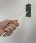 Hand using Glo Fish 15 Ft Glow In The Dark Fiberglass Fish Sticks Kit to insert rod into electrical box on wall.