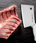 7 Inch Meat Cleaver With High Carbon Steel Blade Textured Slip Resistant Handle NSF Certified Heavy Duty Butchering Knife For BBQ And Kitchen Prep Made In USA next to raw ribs