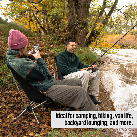 Two people sitting by a river on an ultra lightweight compact camping chair with low back minimalist design, ideal for outdoor relaxation.