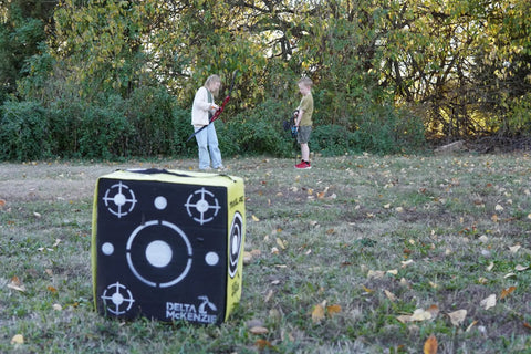 Travel Pro Portable Layered Foam Archery Target in field with children holding bows, 18x16x11 inches for up to 280 FPS use.