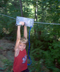 Boy using Backyard Zip Line Kit With 200 Feet Of Galvanized Cable And Aluminum Trolley For Epic Backyard Thrills