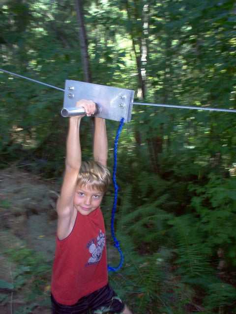 Boy using Backyard Zip Line Kit With 200 Feet Of Galvanized Cable And Aluminum Trolley For Epic Backyard Thrills