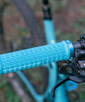 Close-up of blue lock-on mountain bike grip on handlebars, showing textured pattern and secure locking mechanism.