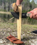 Tracker Knife Outdoor Fixed Blade Bushcraft Camp Knife splitting wood with scout style leather sheath on ground