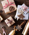 Gift boxes wrapped in brown paper with red ribbons and wooden ornaments on a dark wooden surface.