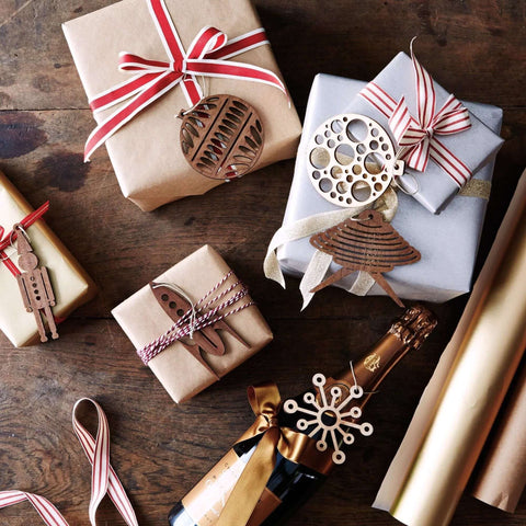 Gift boxes wrapped in brown paper with red ribbons and wooden ornaments on a dark wooden surface.
