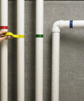 Person applying yellow tape on pipes with blue, red, and green marked, showcasing color separation use.