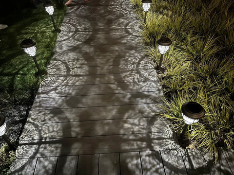 Bright Solar Pathway Lights 4 Pack Outdoor Waterproof Crackle Glass Aluminum Stake Lights illuminating wooden pathway at night