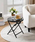 Outdoor Folding Round Patio End Table With Silk Tempered Glass Top And Lightweight Steel Frame beside a white armchair.