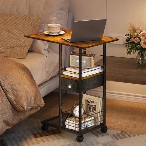 C-Shaped Side Table With Wheels And Large Wood Top beside bed, laptop and coffee on tabletop, drawer visible, metal frame.