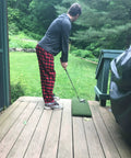 Person using Heavy Duty Golf Practice Mat 10x30 Inch Hitting Strip For Indoor Outdoor Use Accepts Real Tees on wooden deck