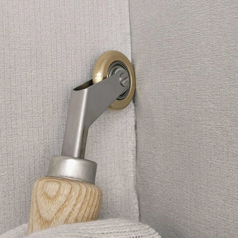 Welding handheld roller with wooden handle and metal neck; brass-toned 40mm wheel rolling on light gray fabric.