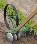 Disk Harrow Attachment on wheel hoe cultivating soil in garden with green plants, ideal for shallow cultivation and weed prevention.