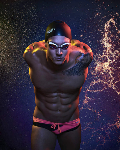 Athlete wearing swim goggles and black swim cap against a starry background