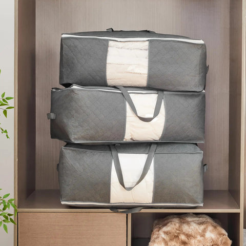 Three grey Roomy 105L Extra Large Storage Bags For Blankets Bedding And Clothes 3 Pack With 4 Handles stacked in closet with clear window.
